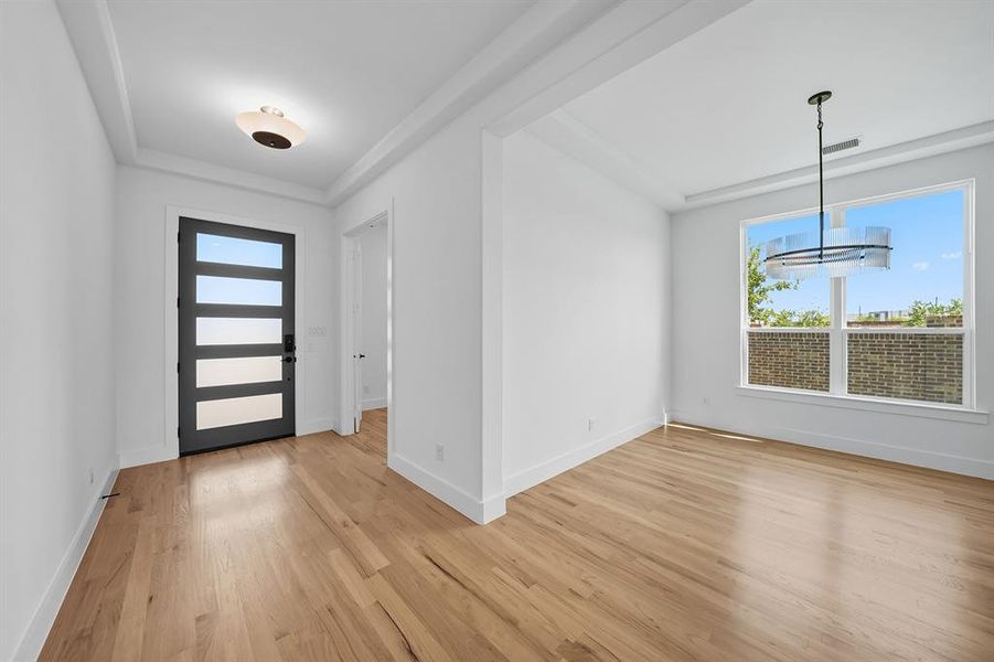 Foyer with light wood-style flooring and a chandelier