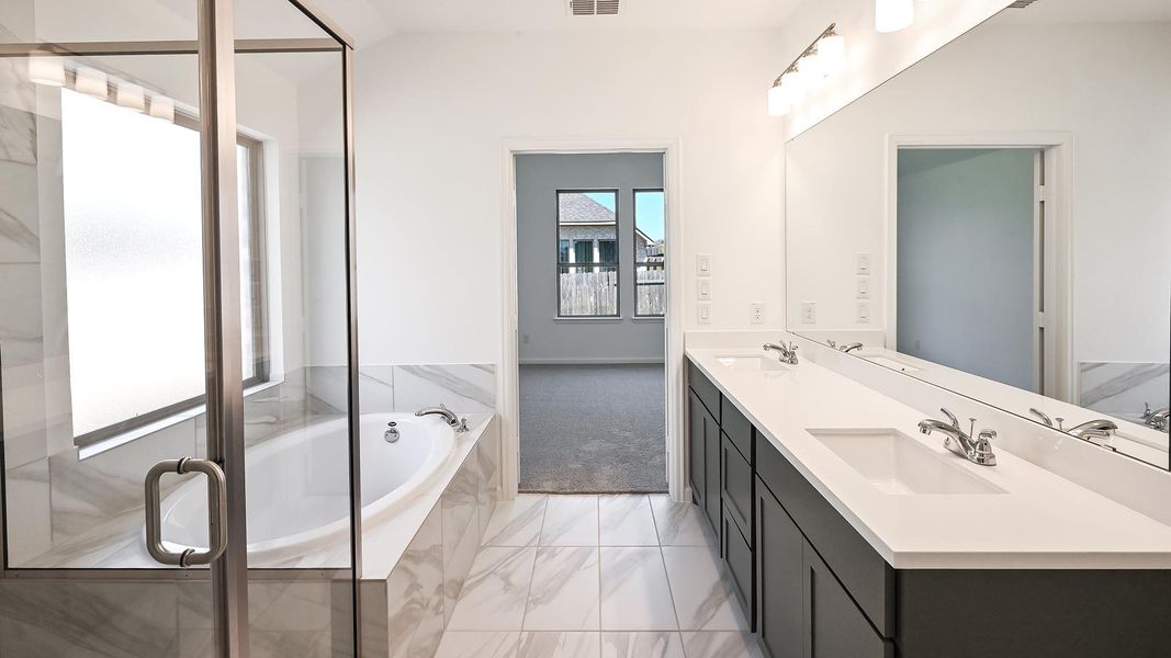 Full bath featuring double vanity, a bath, marble finish flooring, and a shower with shower door Full bath featuring double vanity, a bath, marble finish flooring, and a shower with shower door