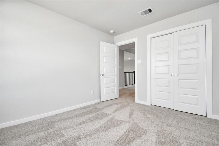 Generously sized secondary bedrooms, complete with spacious closets and soft, inviting carpeting.  Sample photo of completed home with similar plan. As built color and selections may vary.