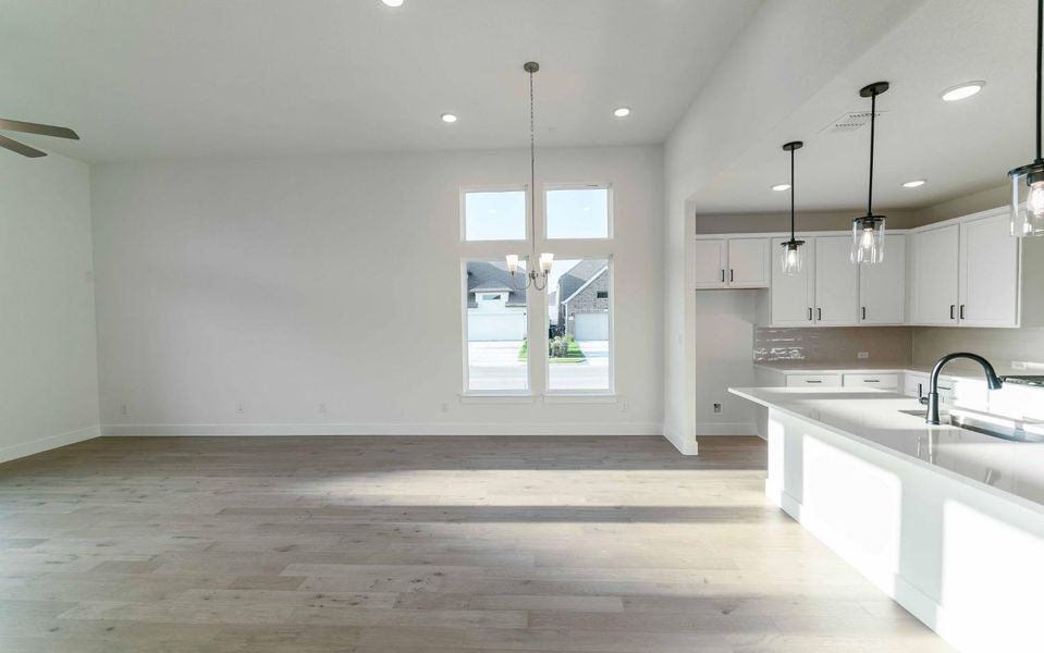 Kitchen with a ceiling fan, white cabinetry, decorative light fixtures, light wood-type flooring, and recessed lighting
