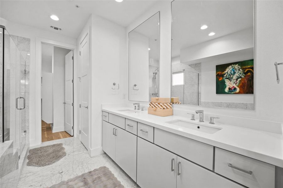 Contemporary bathroom featuring a dual vanity with white countertops, light gray cabinetry, and undermount sinks
