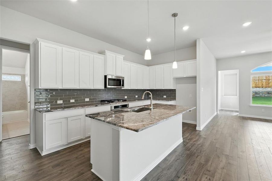 Kitchen featuring stainless steel microwave, dark wood-type flooring, stone countertops, white cabinets, and recessed lighting