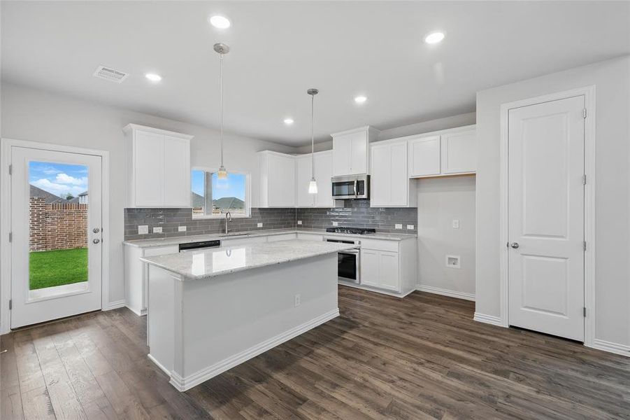 Kitchen with appliances with stainless steel finishes, white cabinetry, tasteful backsplash, a center island, and recessed lighting