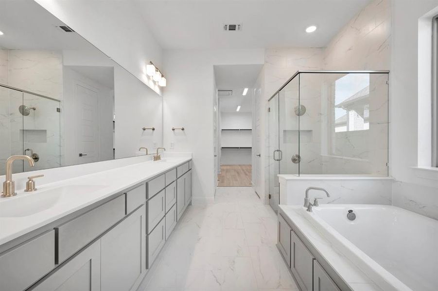 Full bathroom featuring a marble finish shower, double vanity, a garden tub, light marble finish floors, and recessed lighting Full bathroom featuring a marble finish shower, double vanity, a garden tub, light marble finish floors, and recessed lighting