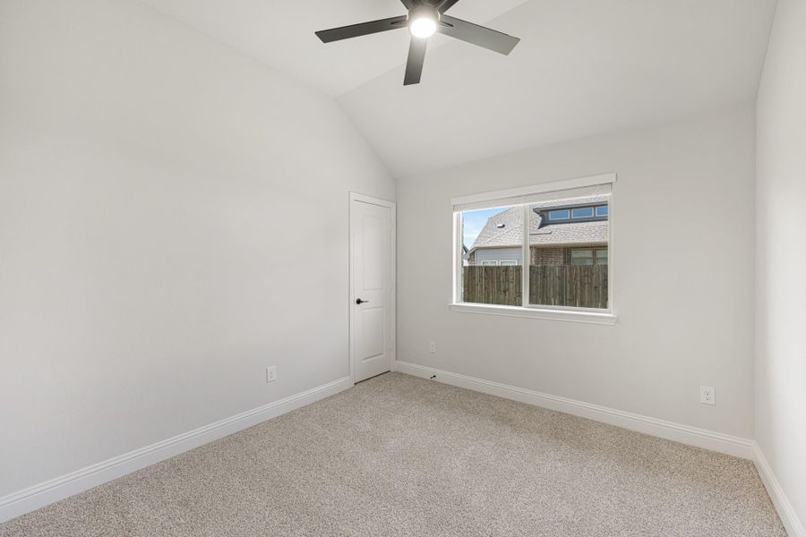 Empty bedroom with vaulted ceiling, ceiling fan, carpet flooring, and a single window