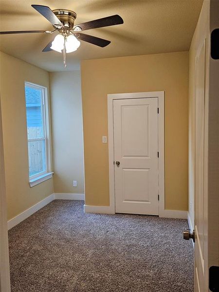 Unfurnished room featuring ceiling fan and carpet