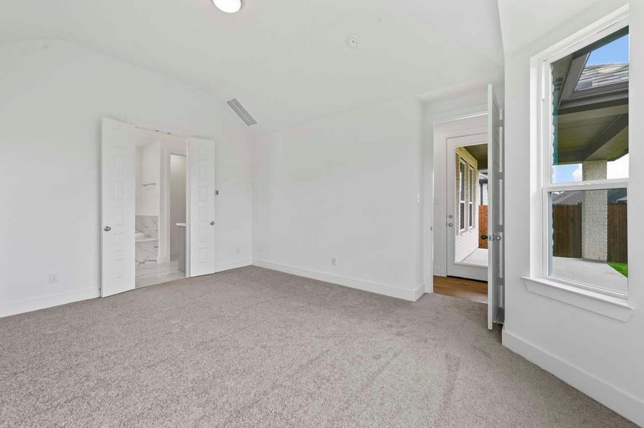 Carpeted spare room featuring vaulted ceiling, baseboards, and visible vents