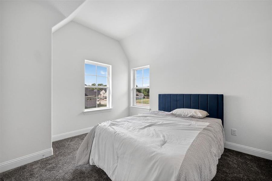 Bedroom with lofted ceiling and dark colored carpet Bedroom with lofted ceiling and dark colored carpet