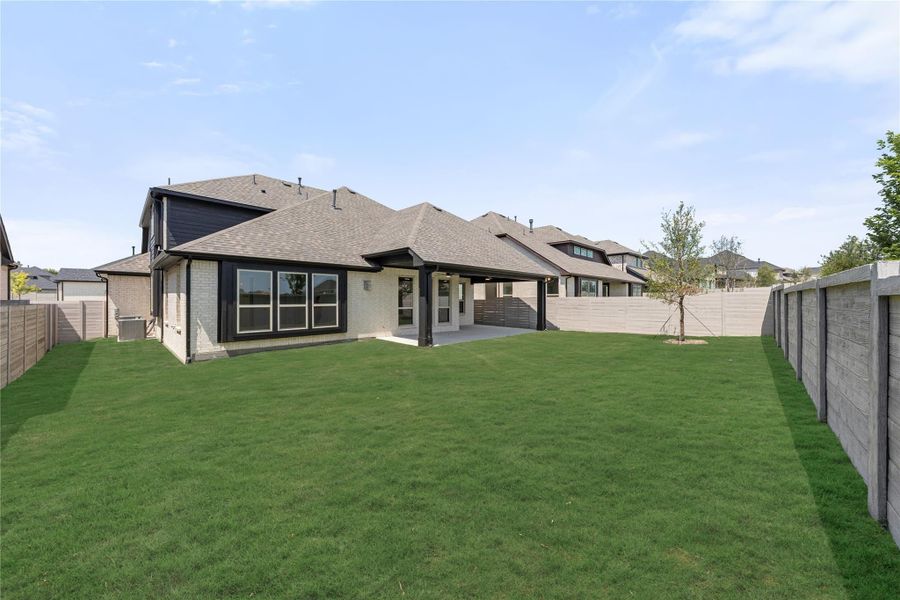 Backyard of a brick home with covered patio, large green lawn, and privacy fence Backyard of a brick home with covered patio, large green lawn, and privacy fence