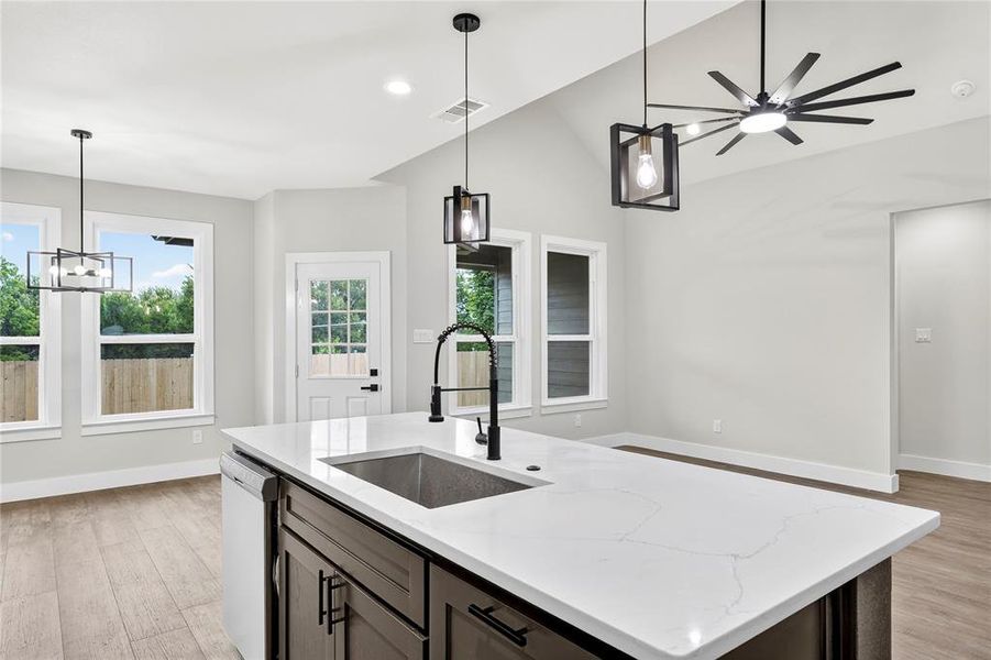 Modern kitchen featuring wood-finish flooring, two-tone cabinetry with white upper and dark lower units, white countertops, and a tiled backsplash