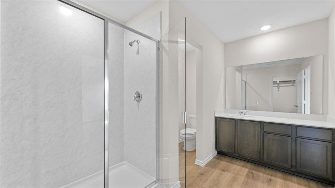 Bathroom featuring a glass-enclosed shower, a wide vanity with dark wood-finish cabinetry, a large integrated mirror, and wood-finish flooring
