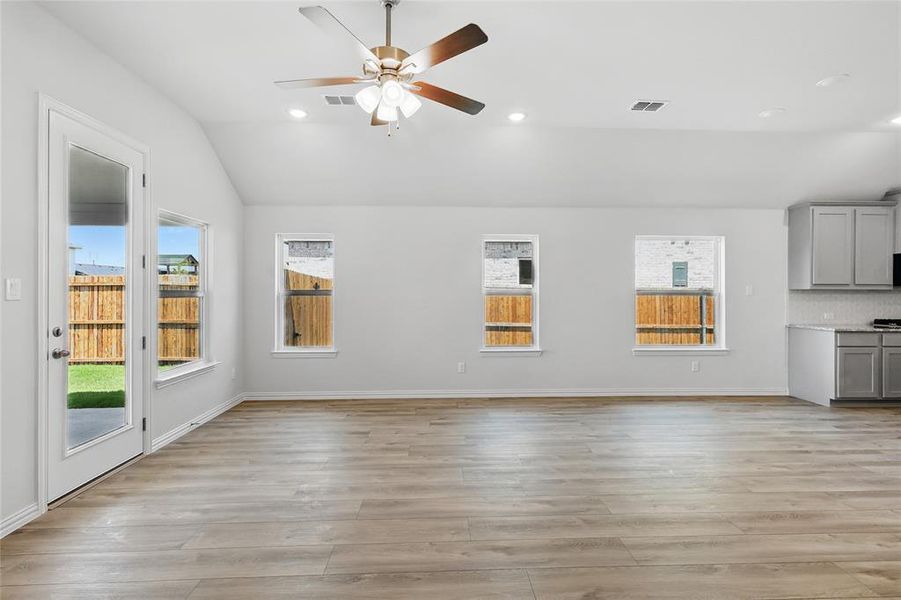 Unfurnished living room with vaulted ceiling, ceiling fan, light wood-style floors, healthy amount of natural light, and recessed lighting