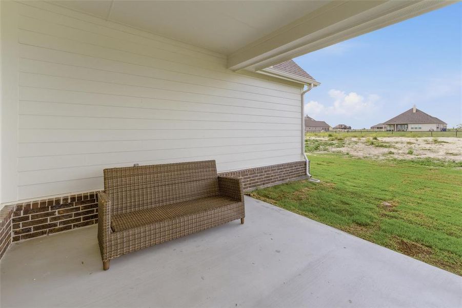 Covered patio with a concrete surface, featuring brick detailing and horizontal siding