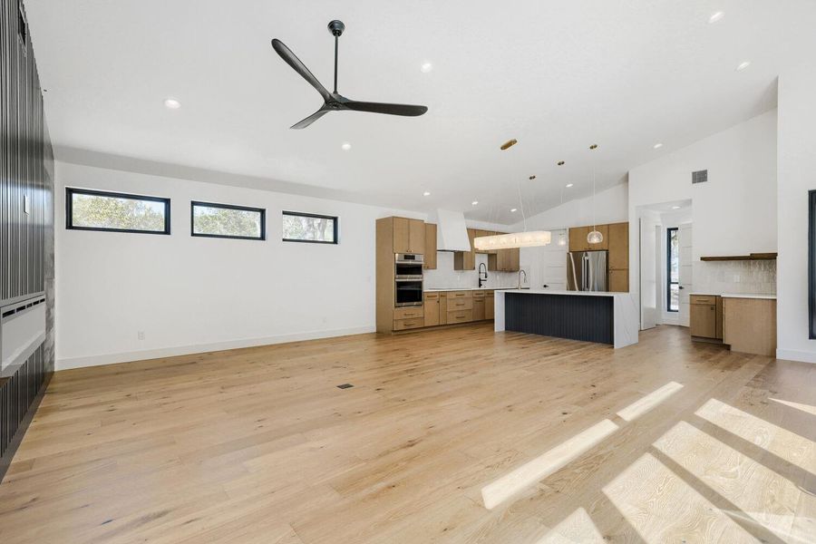 Unfurnished living room featuring ceiling fan, recessed lighting, light wood-style floors, and lofted ceiling Unfurnished living room featuring ceiling fan, recessed lighting, light wood-style floors, and lofted ceiling