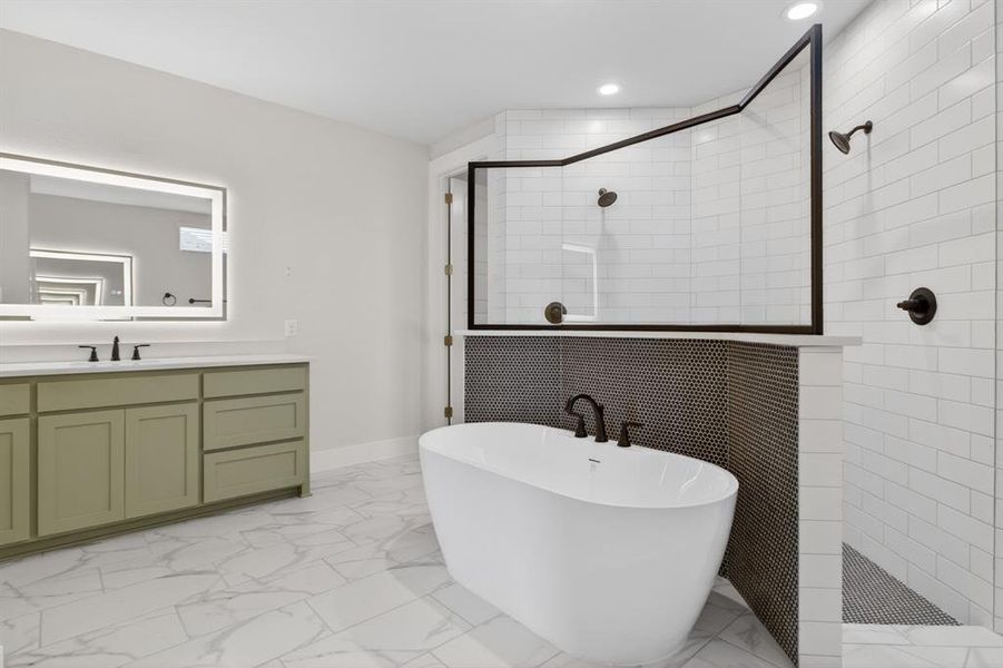 Spacious bathroom featuring a freestanding tub, dual-head shower with subway tile surround, double vanity with a light green finish, back-lit mirror, and patterned floor tile Spacious bathroom featuring a freestanding tub, dual-head shower with subway tile surround, double vanity with a light green finish, back-lit mirror, and patterned floor tile