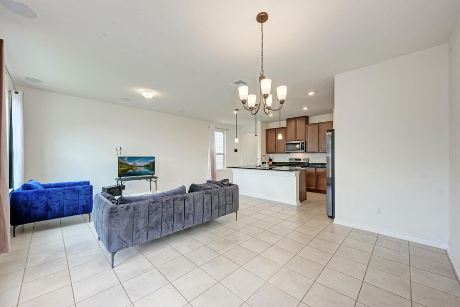 An open floorplan with durable tiled flooring seamlessly connects the living space to a well-appointed kitchen.