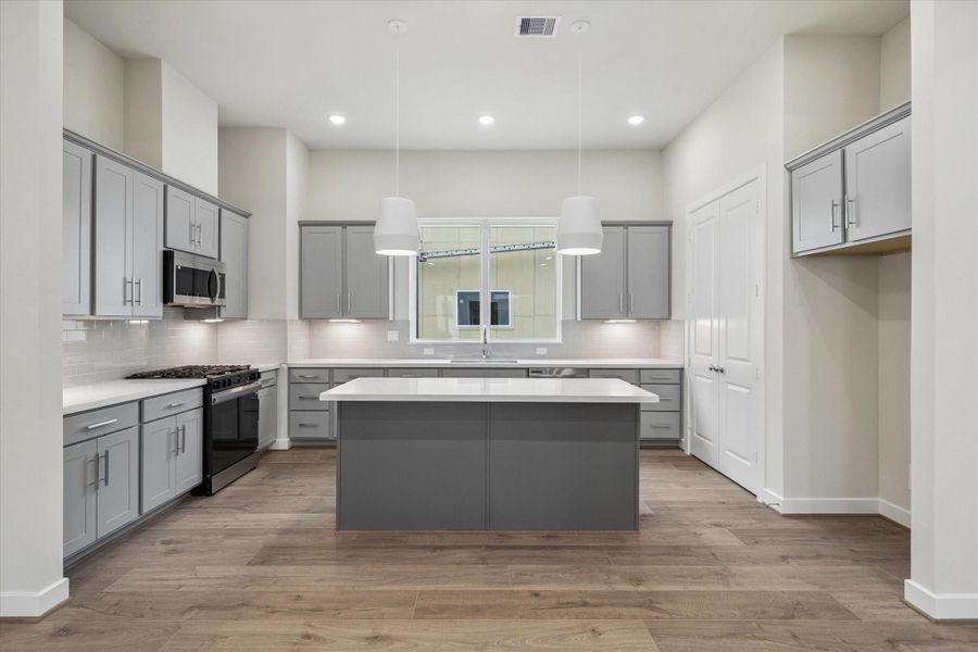 quartz island, gas range cooktop, large pantry, thoughtful lighting design.