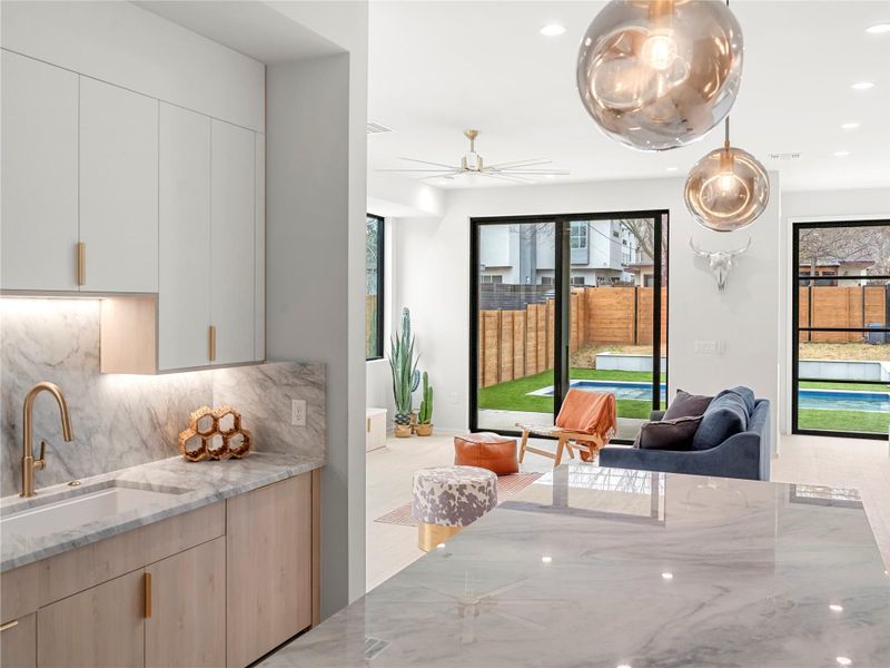 Kitchen featuring light stone counters, modern cabinets, light wood finish cabinetry, recessed lighting, and ceiling fan