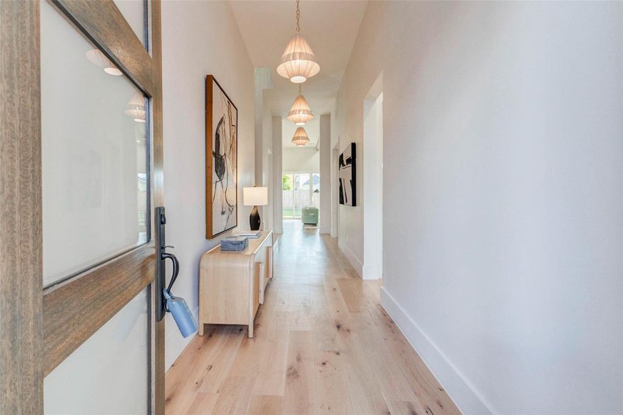 A refined interior arrival showcasing wide-plank hardwood floors, soft natural light, and designer pendant fixtures.