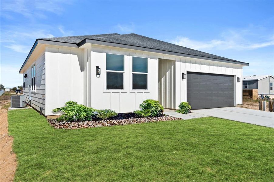 You're looking at a modern single-story home with a clean white exterior, featuring large windows and a two-car garage. The property boasts a well-maintained lawn and a simple yet elegant landscaping with a rock garden.