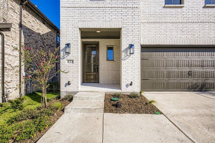 Property entrance featuring brick siding, driveway, and an attached garage Property entrance featuring brick siding, driveway, and an attached garage