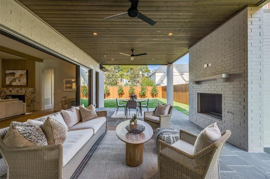 Fenced backyard featuring a patio area, an outdoor living space with a fireplace, ceiling fan, and outdoor dining space Fenced backyard featuring a patio area, an outdoor living space with a fireplace, ceiling fan, and outdoor dining space