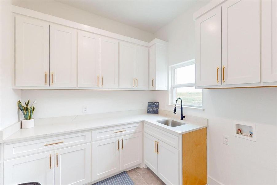 Kitchen featuring light stone counters, sink, light tile patterned floors, and white cabinetry