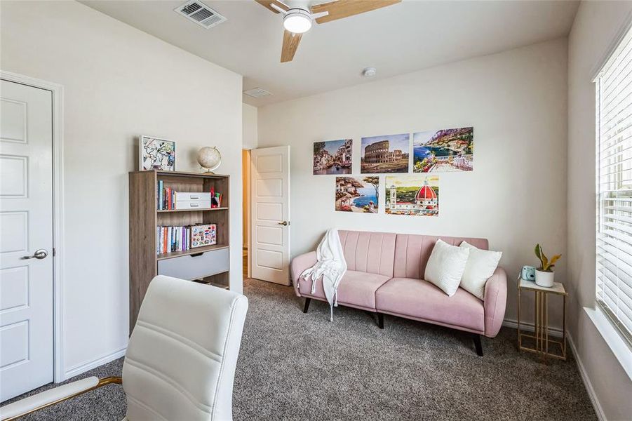 Living area with ceiling fan, carpet floors, visible vents, and baseboards