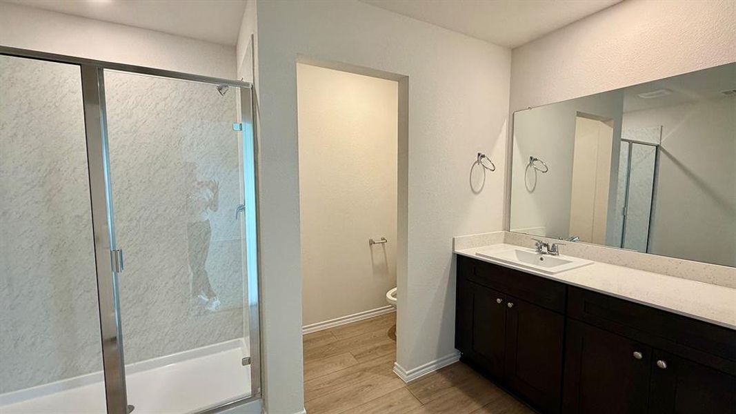 Bathroom featuring a glass-enclosed shower, a double vanity with a light-colored countertop, and dark wood-finish cabinetry