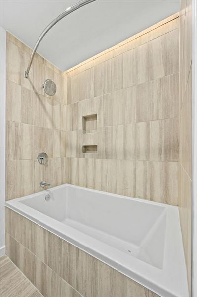 Bathroom featuring tiled shower / bath and tile walls Bathroom featuring tiled shower / bath and tile walls
