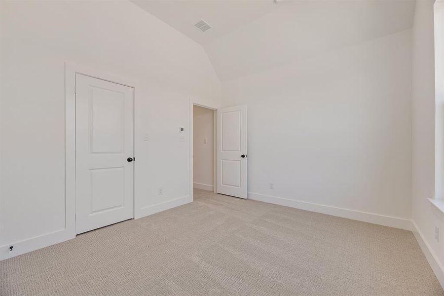 Unfurnished bedroom featuring light colored carpet and high vaulted ceiling Unfurnished bedroom featuring light colored carpet and high vaulted ceiling