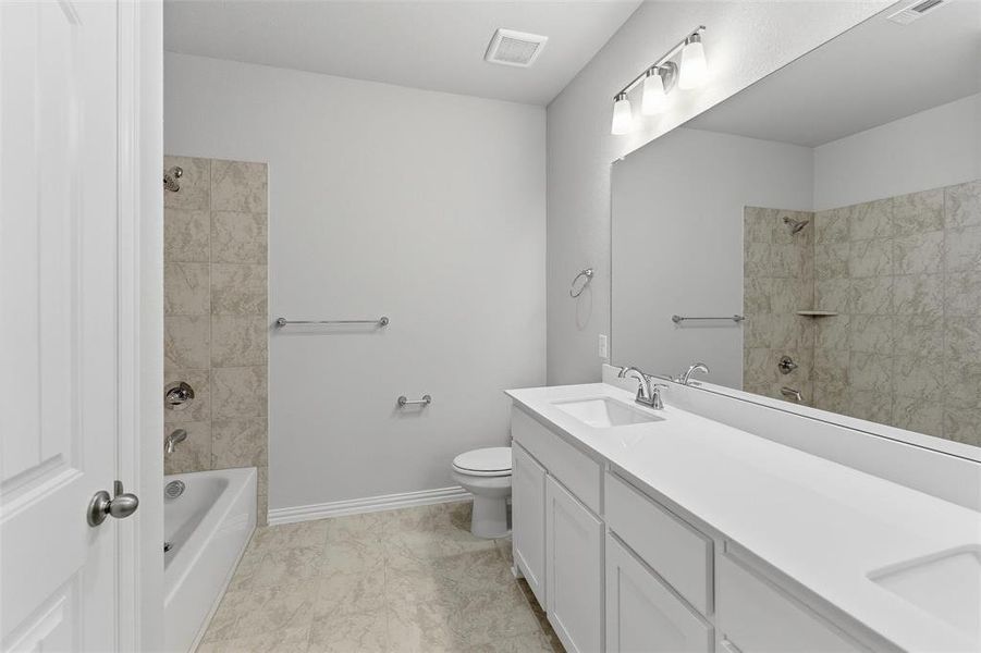 Bathroom featuring a double vanity with white cabinetry and integrated sinks, a full-width mirror, and a bathtub with tiled surround Bathroom featuring a double vanity with white cabinetry and integrated sinks, a full-width mirror, and a bathtub with tiled surround