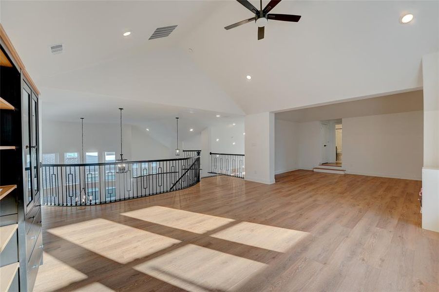 Spare room featuring visible vents, high vaulted ceiling, vinyl looring, and a ceiling fan