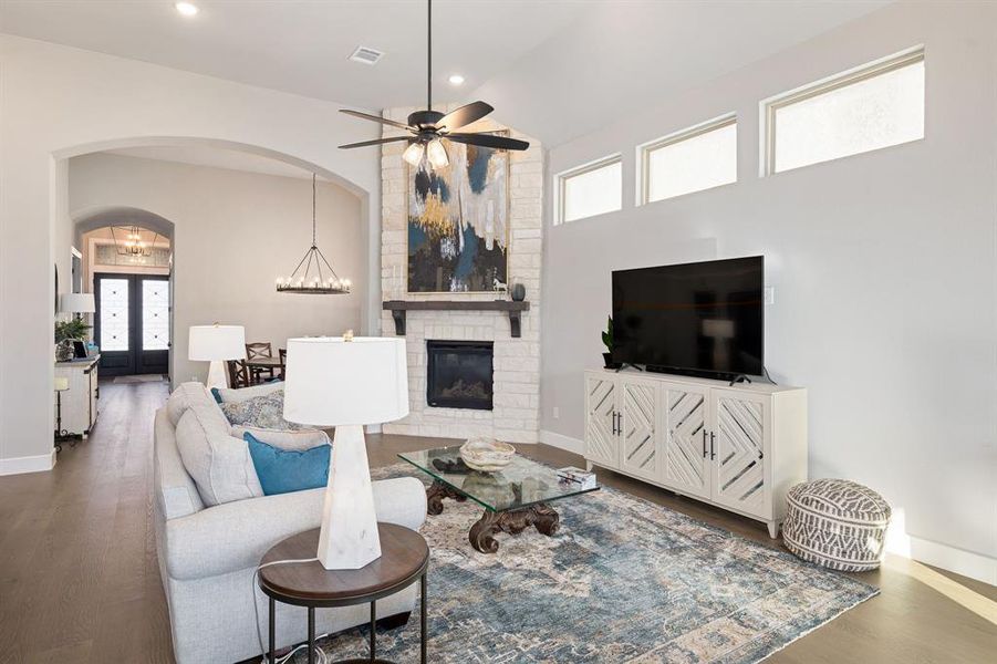 Living room featuring lofted ceiling, a stone fireplace, dark hardwood / wood-style floors, and ceiling fan