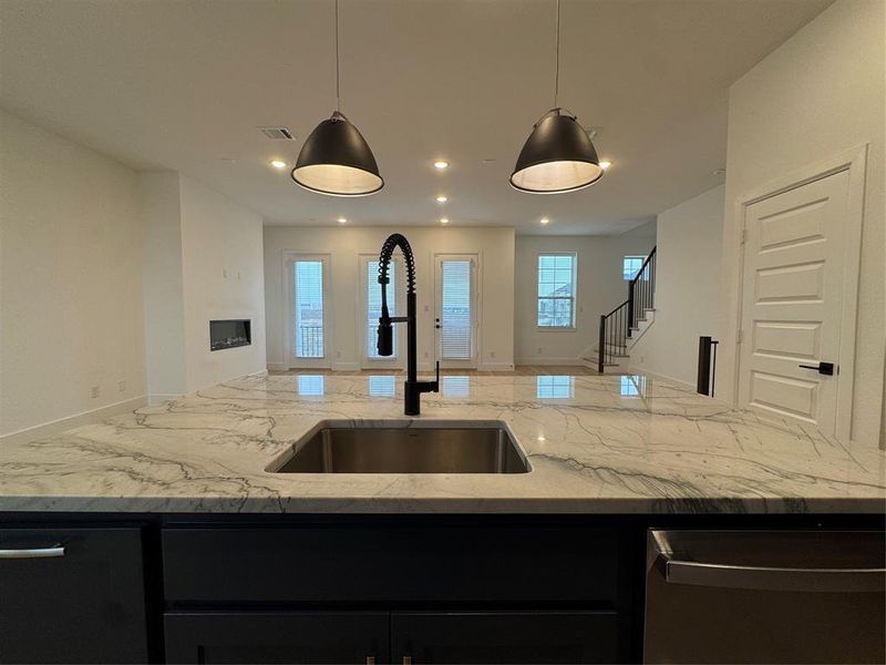 Kitchen with dark cabinetry, visible vents, open floor plan, and a sink