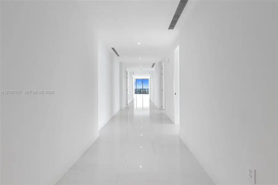 Hallway featuring polished tile flooring, recessed ceiling lighting, and floor-to-ceiling windows
