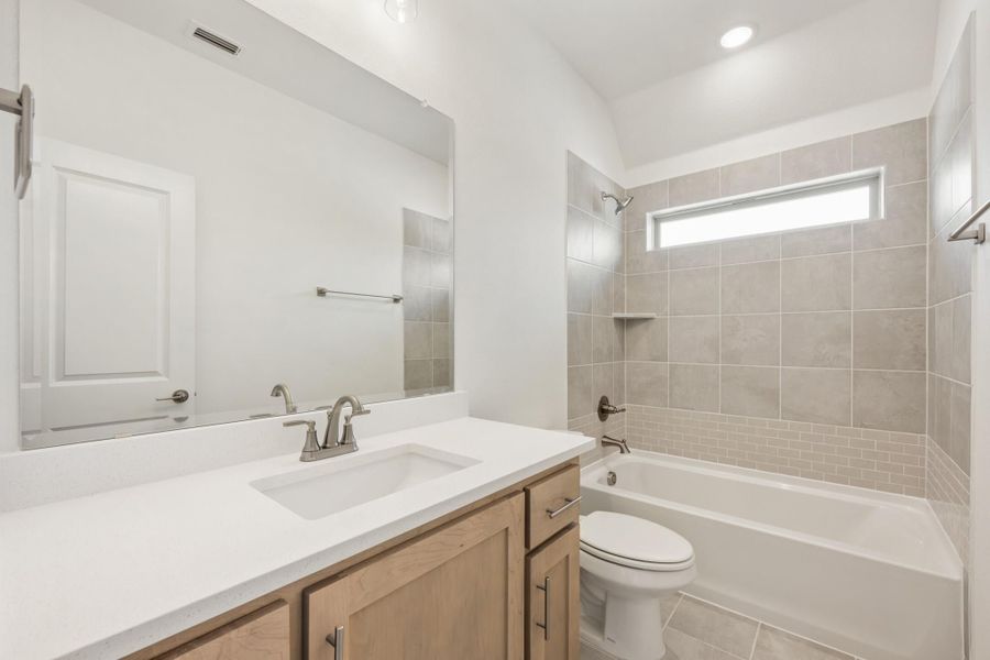 Bathroom with single vanity, large mirror, and tub-shower combo with gray tile surround