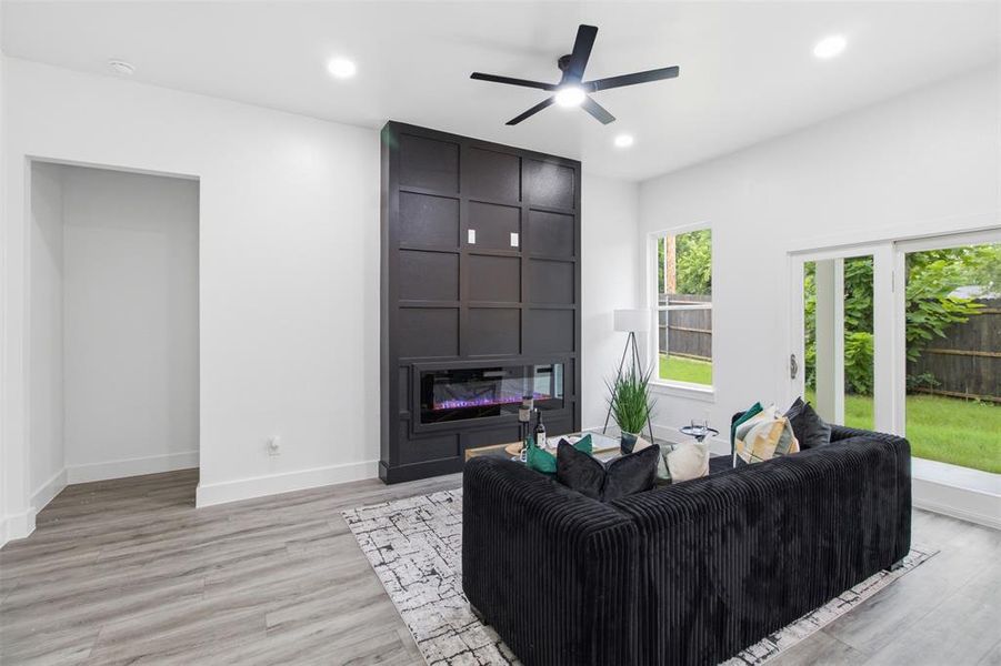 Living space featuring a tall paneled accent wall with an integrated electric fireplace
