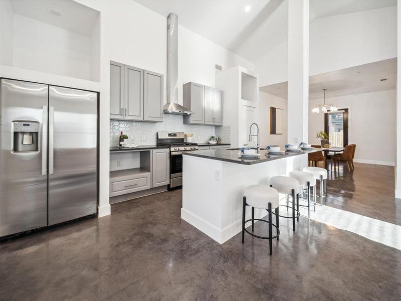 Kitchen featuring a kitchen breakfast bar, stainless steel appliances, gray cabinetry, and an island with sink