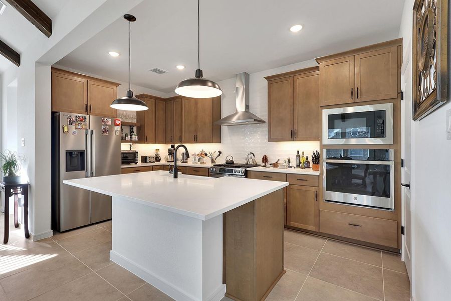 This farmhouse modern kitchen features sleek wood cabinetry, stainless steel appliances, and a spacious island with a quartz countertop. Very functional space for meal prep and entertaining!
