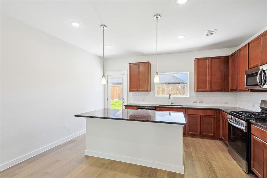 Kitchen featuring light hardwood / wood-style floors, dark stone countertops, sink, and stainless steel appliances