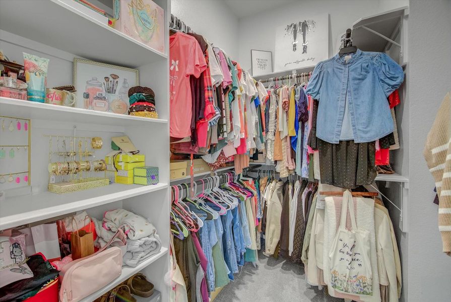 Her spacious closet offers upper and lower hanging rails, complemented by curated shelving ideal for displaying shoes, handbags, and jewelry.