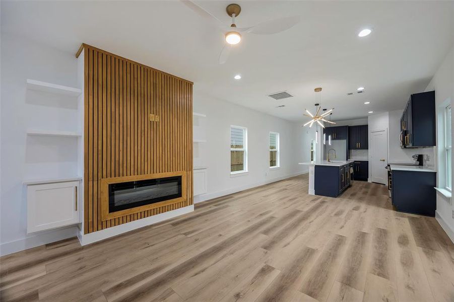 Unfurnished living room with ceiling fan, sink, and light wood-type flooring