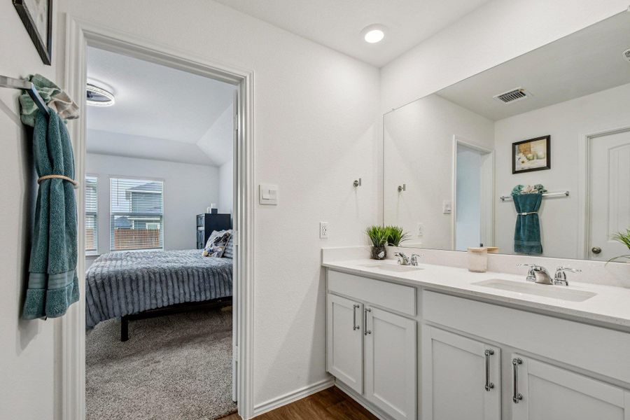Ensuite bathroom featuring double vanity and dark wood-style flooring