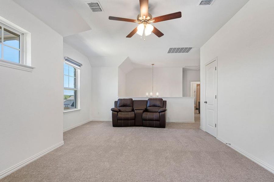 Sitting room featuring a ceiling fan, light carpet, a chandelier, and vaulted ceiling Sitting room featuring a ceiling fan, light carpet, a chandelier, and vaulted ceiling