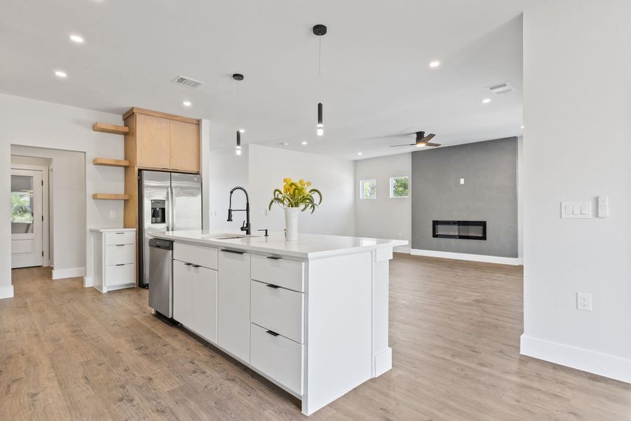 Kitchen with open shelves, white cabinets, decorative light fixtures, a fireplace, and recessed lighting