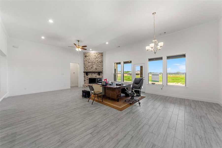 Office area with a fireplace, a ceiling fan, recessed lighting, light wood-type flooring, and a chandelier