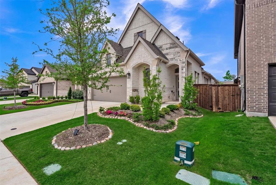 Two-story exterior featuring a light-colored brick facade with stone accents, an arched entryway, and a dark shingled roof Two-story exterior featuring a light-colored brick facade with stone accents, an arched entryway, and a dark shingled roof