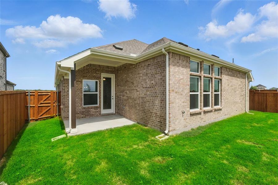 Rear view of house featuring a patio, brick siding, and a gate