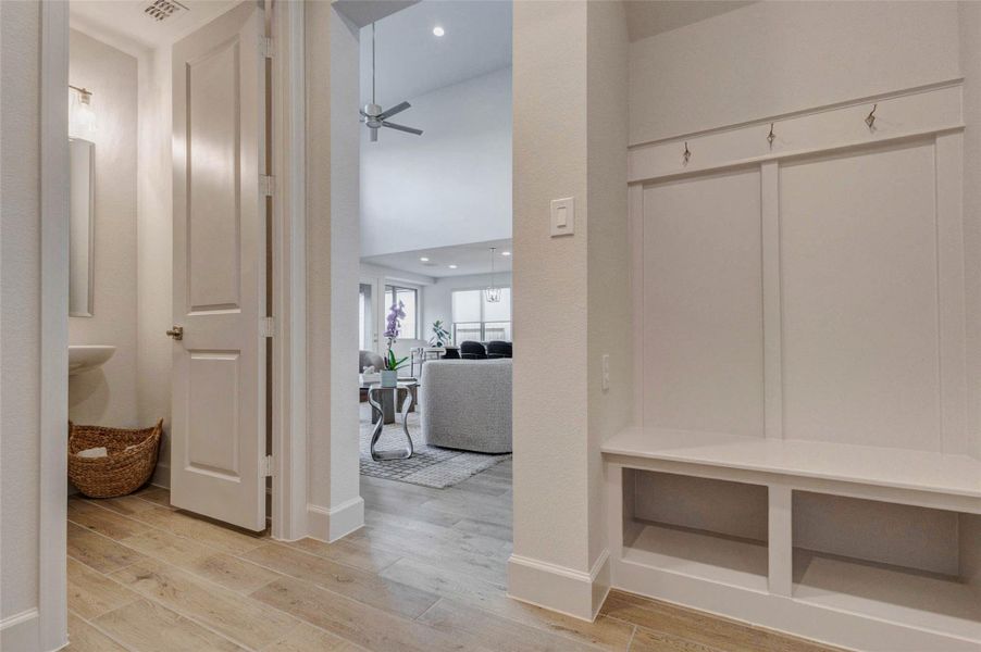 Modern, bright entryway with a built-in bench and hooks for organization. It leads to an open living area with a cozy seating arrangement and a ceiling fan, offering a welcoming and functional space. Modern, bright entryway with a built-in bench and hooks for organization. It leads to an open living area with a cozy seating arrangement and a ceiling fan, offering a welcoming and functional space.